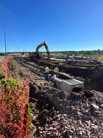 The new storm sewer system on the south side of the Vibes parking lot. Pipes are being laid in an excavated area of dirt.