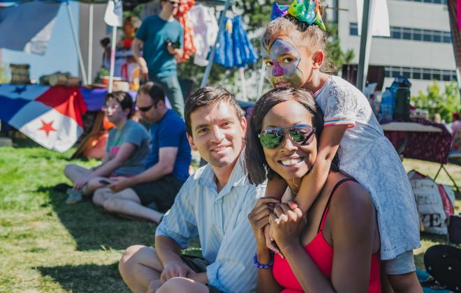 A family sits in a park smiling at the camera