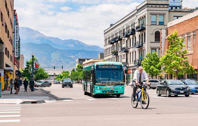 busy downtown street with pedestrians, bike commuters, bus, and personal vehicles