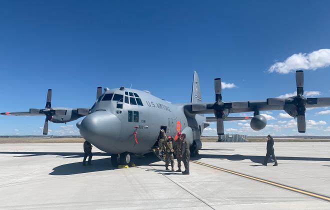 people standing next to a large tanker plane